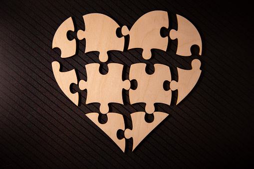 Shape of heart made from cardboard puzzles. Valentines Day background with heart from jigsaw puzzle parts on white background.