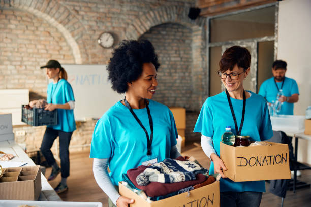 istock Happy female volunteers with donation boxes at humanitarian aid center. 1996172995