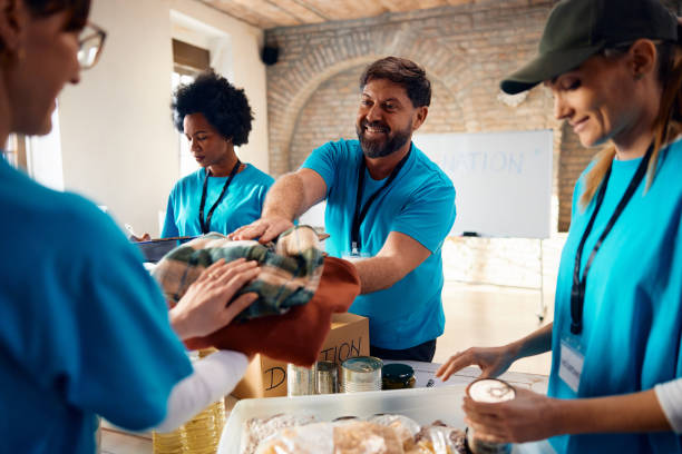 istock Group of happy volunteers sorting donations while working at charitable foundation. 1996176056