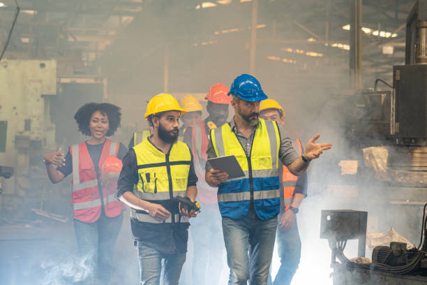 istock Engineer in uniform and helmet using tablet computer at factory. Worker with safety helmet checking quality in manufacturing. 1996215427