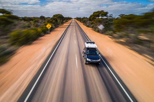 Motion blur of car with camper driving along a long straight road in Australia. Captured while crossing the Nullarbor.