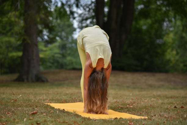 A middle-aged woman is doing yoga in the park stock photo