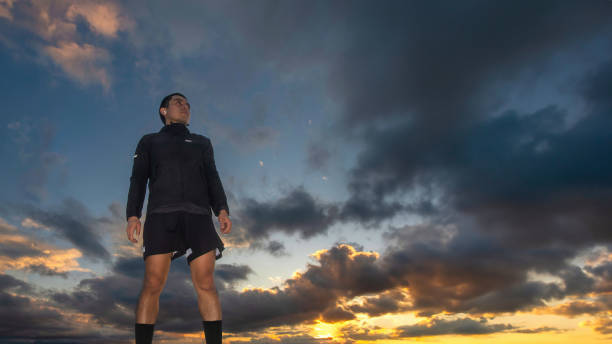 Young sporty runner man with sunset sky in the background and space for text