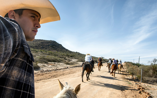 A Man taking a walk with friends on horseback in hat through semi-deserted countryside, with space for text