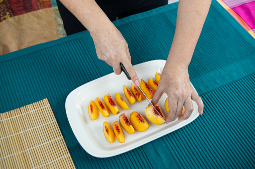 Hands Artfully Preparing Mouthwatering Peach Creations for Dining Pleasure