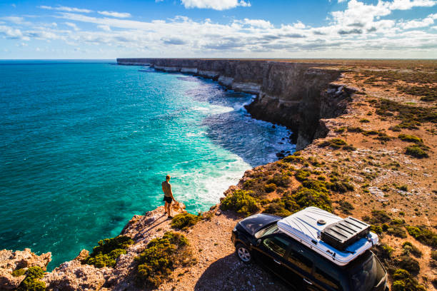 Aerial view of car parked with camper and young man overlooking the Great Australian Bight Aerial view of car parked with camper and young man overlooking the Great Australian Bight. Captured while crossing the Nullarbor. outback stock pictures, royalty-free photos & images