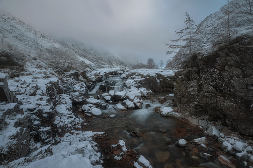 Waterfall in winter on the River Coe and a snow bank at in Glencoe in the Scottish Highlands. High quality photo