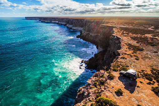 Aerial view of car parked with camper and young man overlooking the Great Australian Bight. Captured while crossing the Nullarbor.
