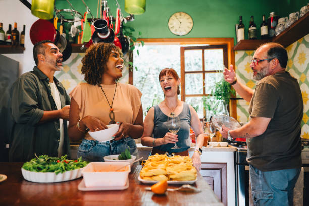 istock Two laughing mature couples making a meal together at home 1996314744