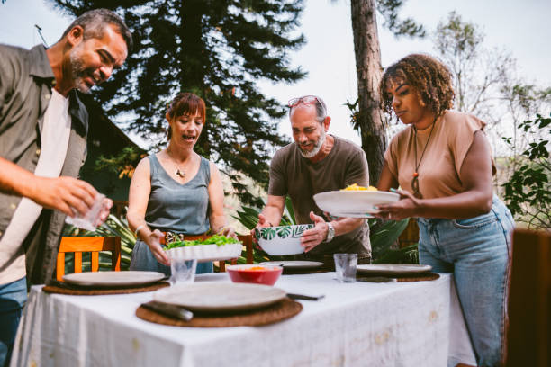 istock Smiling mature friends putting lunch on a dining table outside in summer 1996315773