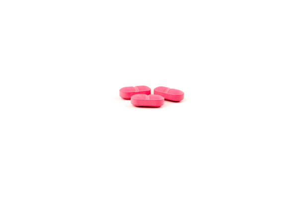 istock Three pink capsule pills grouped and isolated on white background 1996342623
