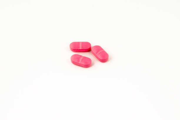 istock Three pink capsule pills grouped and isolated on white background 1996342628