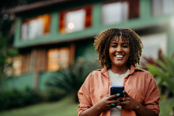 istock Smiling woman texting on the phone while standing in her back yard 1996357690