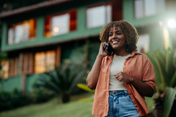 istock Smiling woman talking on the phone while standing in her back yard 1996357694