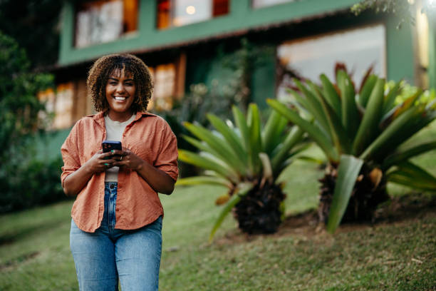 istock Smiling woman texting on the phone outside in her back yard 1996357695