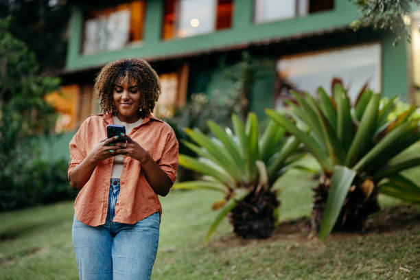 Young woman smiling while texting on the phone in her back yard