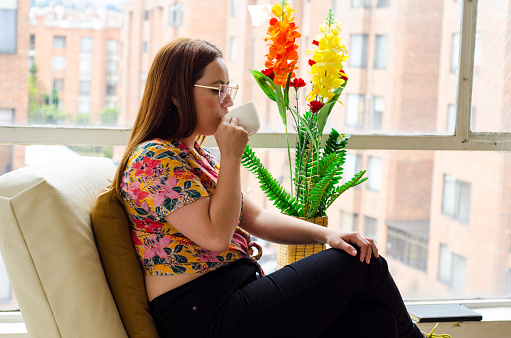 beautiful Mid Adult woman drinking a cup of coffee on her living room