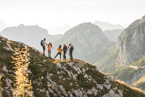 Mountain ridge adventure, diverse friends hike with backpacks and hiking poles.