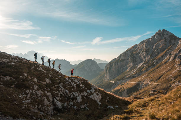 Diverse Friends Enjoying Sunny Mountain Hike With backpacks and hiking poles, diverse friends trek together on a sunny day, embracing the joy of hiking in the mountains. julian alps stock pictures, royalty-free photos & images