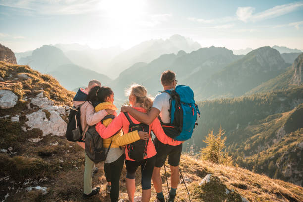 Diverse Friends Embracing and Having Fun at Sunny Julian Alps A diverse group embraces and has fun during their sunny day hike through the Julian Alps, taking in the beautiful views in the distance. julian alps stock pictures, royalty-free photos & images