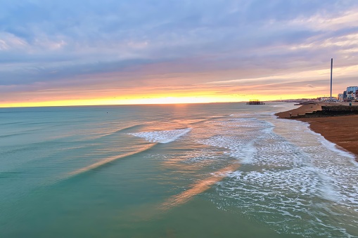 Brighton, United Kingdom - March 04 2022: view of a mysterious sunset reflections on the surface of the water and pebble beach