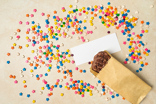 High angle view of chocolate cookies in a brown paper bag over a tble with sugar sprinkles and white label