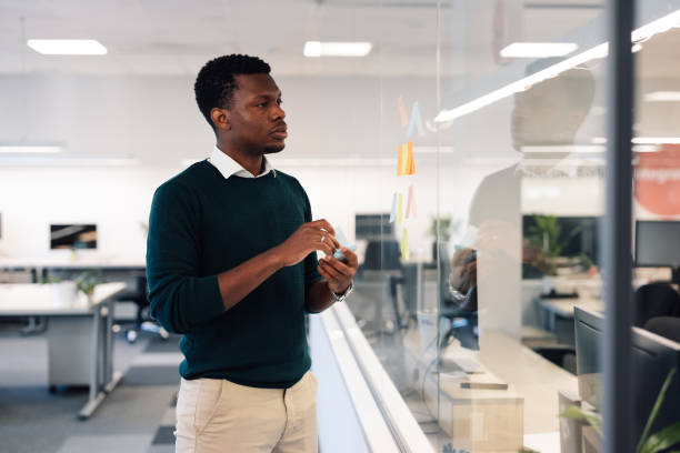 istock African american man using colorful sticky notes on the glass wall in the office 1996395098
