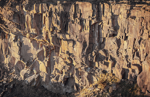 View of Spectacular vertical walls cliffs of Salisbury Crags. Crumbling rock cliff wall texture with cuts and shadows of The granite rock, Nature stone background, Space for text, Selective focus.