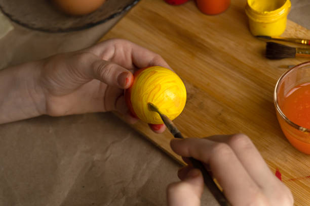 istock The child takes a white egg and paints it with bright colors 1996440450
