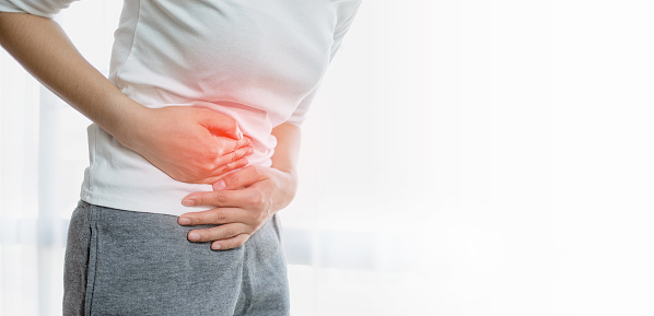 Young woman put her hand on her stomach because she had a very bad stomachache. menstrual pain, gastritis or diarrhoea. Healthcare medical concept.