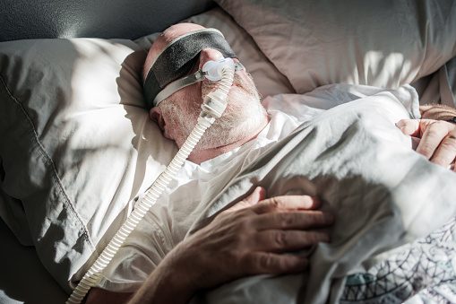 Mature Man Sleeping with a CPAP (Continuous positive airway pressure) Machine after being diagnosed with Sleep Apnea