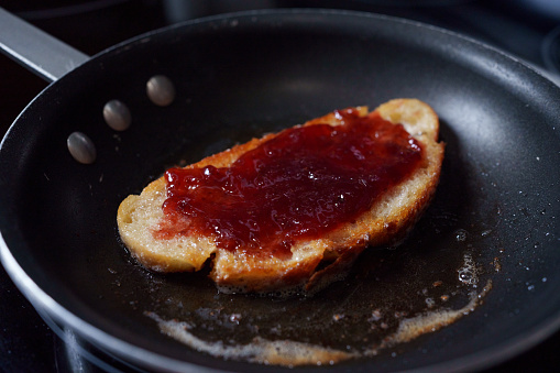Toasted Slice of SourDough Bread In a Pan with Butter, Toasting to a Golden Brown Topped With Strawberry Jam