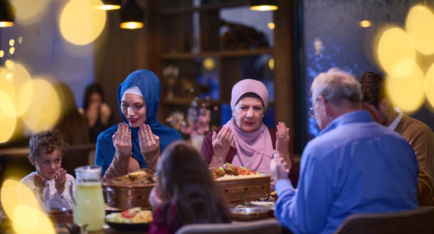 istock In a modern restaurant setting, a European Islamic family comes together for iftar during Ramadan, engaging in prayer before the meal, uniting tradition and contemporary practices in a celebration of faith and family 1996526935