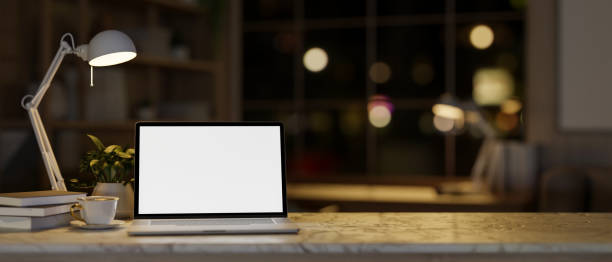 istock A cozy home office workspace at night with a white-screen laptop mockup and decor on a marble table. 1996640194
