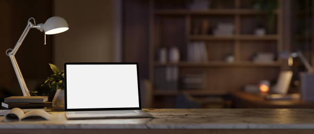 istock A cozy home office workspace at night with a white-screen laptop mockup and decor on a marble table. 1996640713