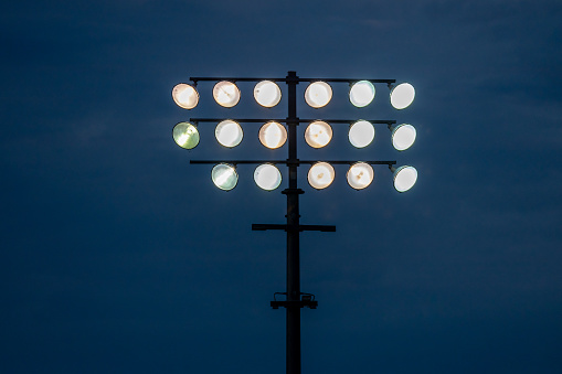 This image shows a view of illuminated outdoor ballpark stadium lights against a darkened sky.