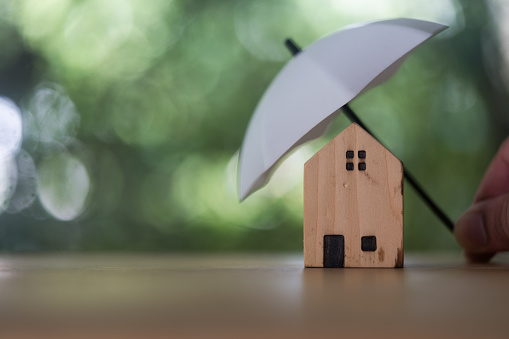 Broker agent use white small umbrellas cover with house, purchase and sale contracts and mortgages including fire insurance. Home insurance for upcoming losses. Insurance is risk control