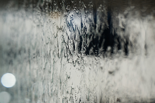 In a close-up capture, the texture of glass through which water flows is beautifully depicted, showcasing intricate patterns and the fluidity of movement in a mesmerizing display.
