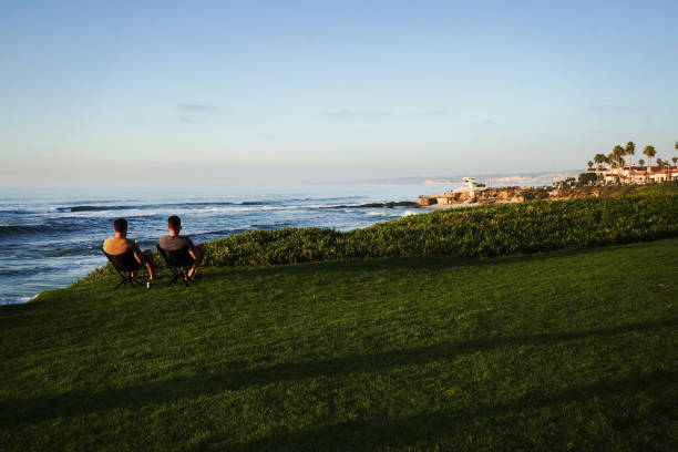 Two men at sunset in San Diego Cuvier Park/ La Jolla- San Diego, CA ,USA- October 17, 2023.  Two men sitting in beach chairs are cliffside at Cuvier Park.  The sun is setting over the ocean and the two are reading books and relaxing. bluff knoll stock pictures, royalty-free photos & images