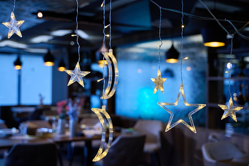 In a modern restaurant, the ambiance is transformed by the presence of sparkling Islamic symbolic Ramadan decorations, creating a festive and culturally rich atmosphere.