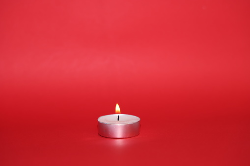 A single candle on a red background with copy space for text.