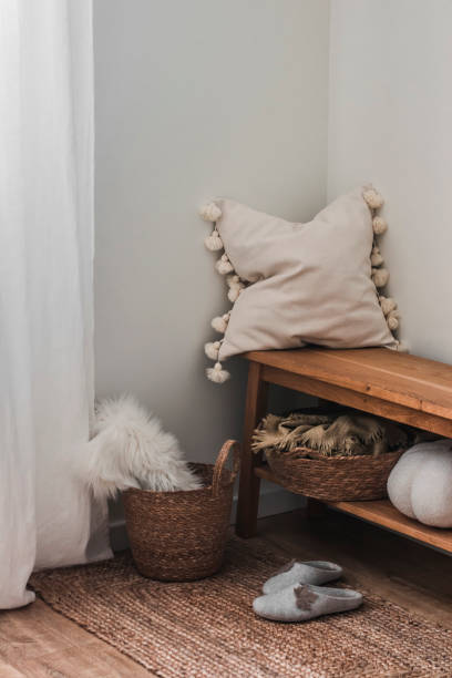 istock A cozy home interior - an oak bench with a decorative pillow, a carpet, a plaid in a basket in the corner of the living room 1996825360