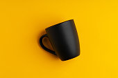 Ceramic mug on yellow studio background close up