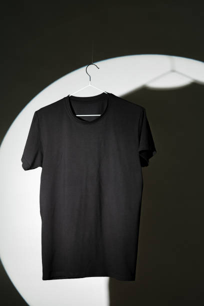 istock Plain black T-shirt hanging on hanger on gray background 1996986098