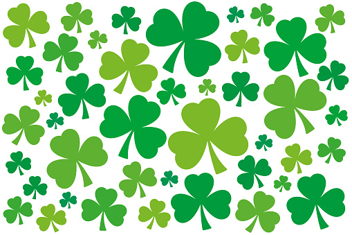Numerous shamrocks, green three-leaf clover background. Randomly arranged, slightly twisted trefoils with different shades of green. Symbol of Ireland, used by Saint Patrick as Holy Trinity metaphor.