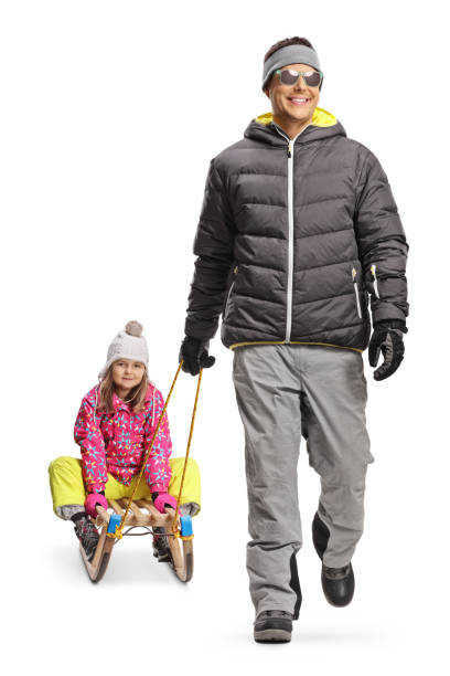 istock Father pulling daughter on a wooden sled and walking towards camera 1997048961