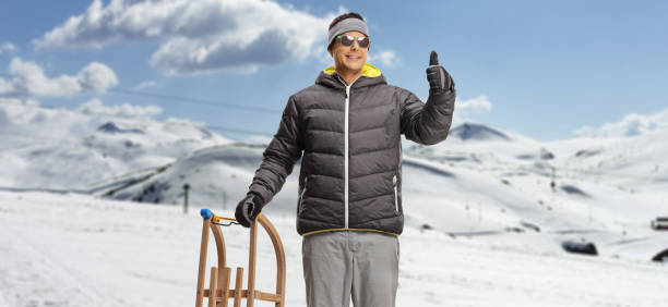 istock Man on a snowy mountain standing with a wooden sleigh 1997048963