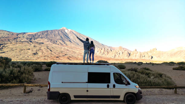 istock Two People Standing on Top of a Van in the Desert 1997055905