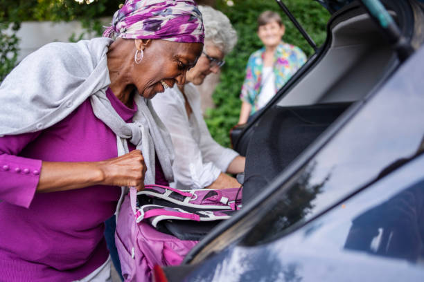 groupe souriant de femmes âgées emballant le coffre de leur voiture avant un voyage en voiture - active seniors enjoyment driveway vitality photos et images de collection