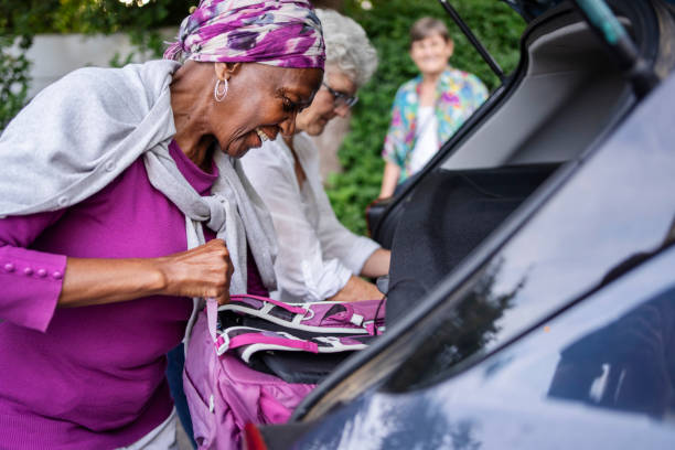 smiling group of senior women packing their car trunk before a road trip - active seniors enjoyment driveway vitality imagens e fotografias de stock